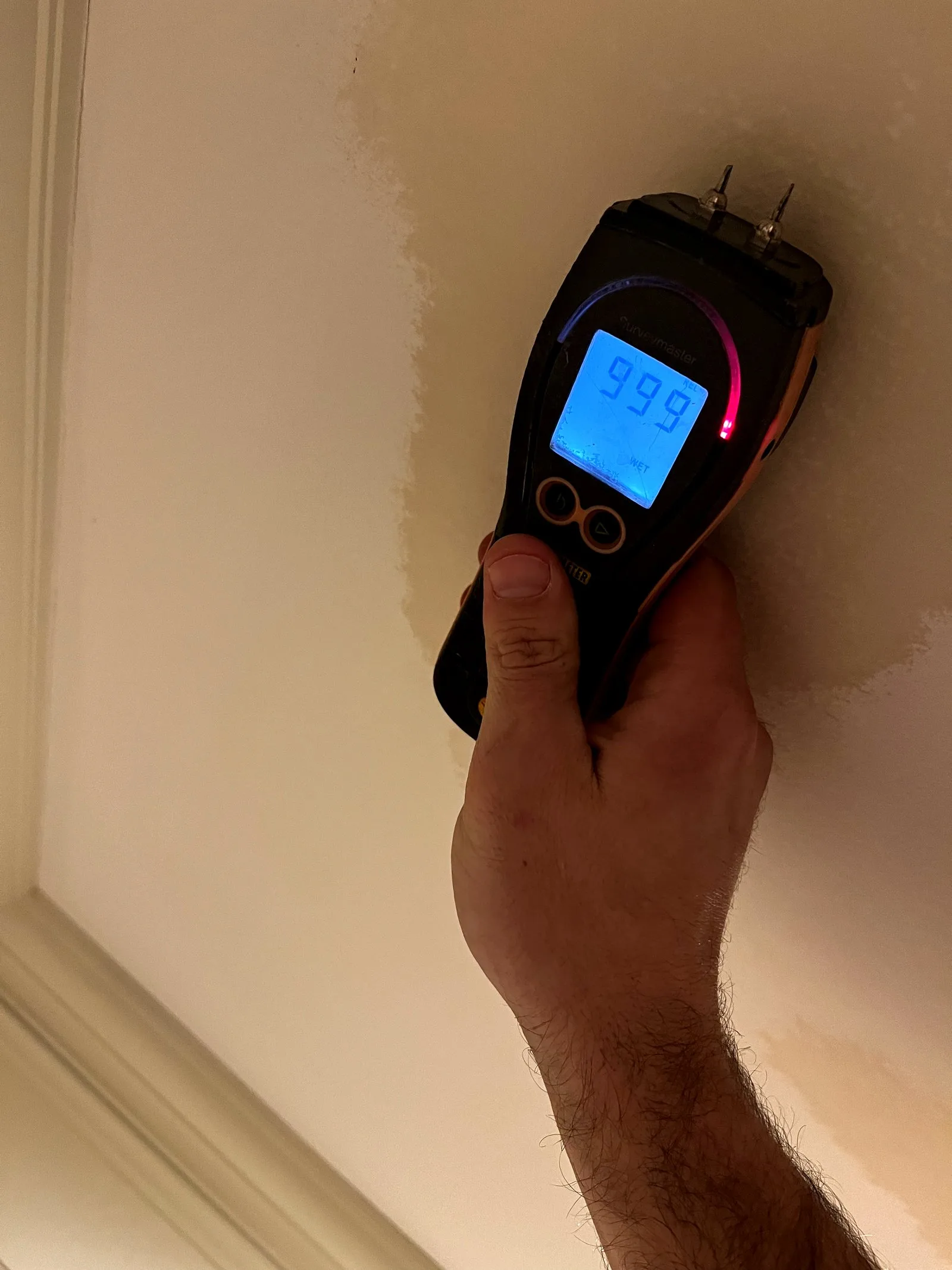 Moisture meter at 999 documenting critical water saturation in a wall cavity